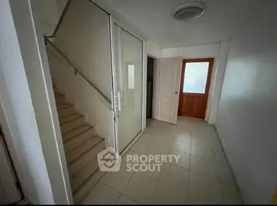 Spacious interior hallway with staircase and glass door, ideal for modern living.