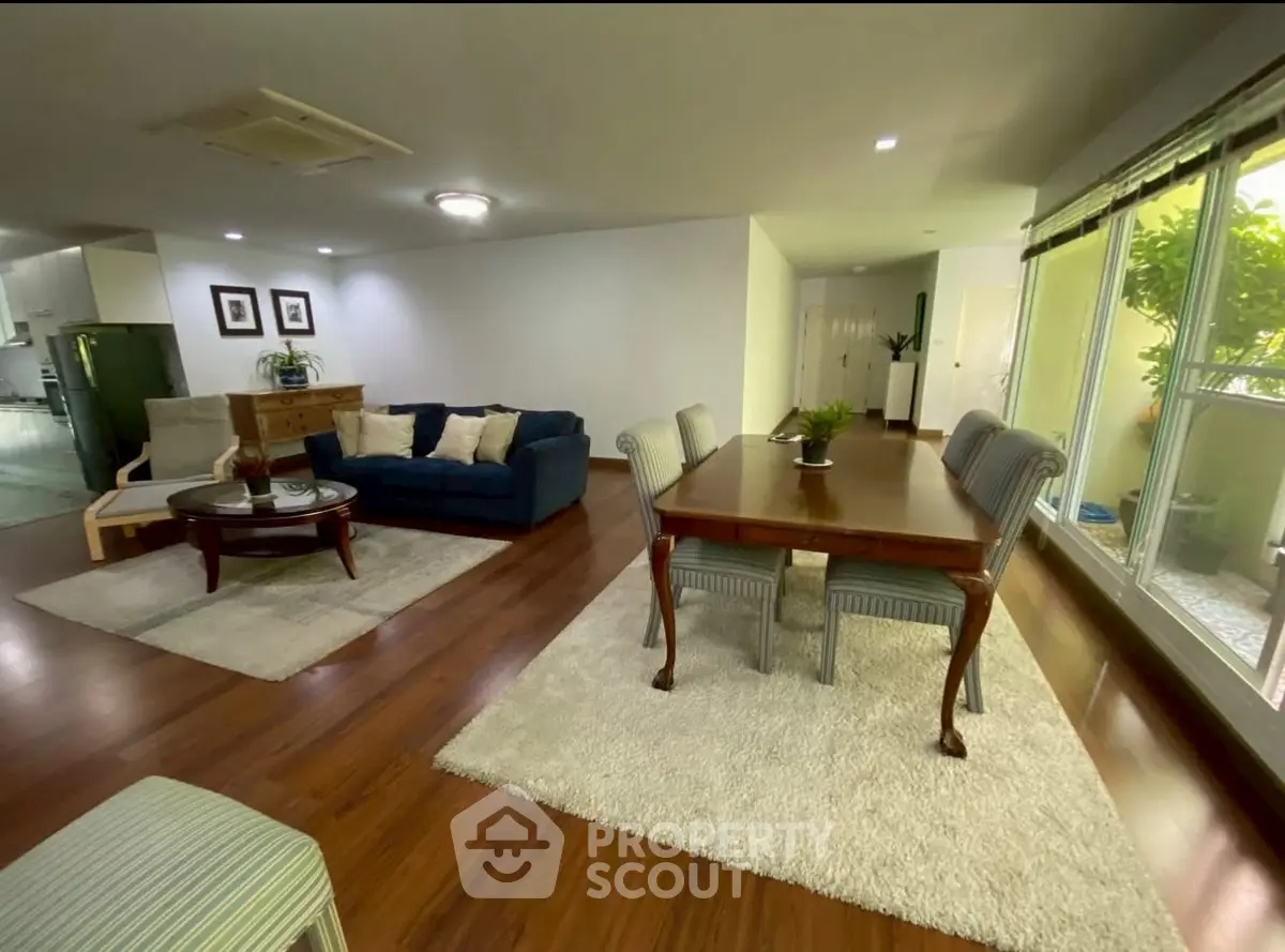 Spacious open-plan living and dining area with elegant furnishings and large windows.