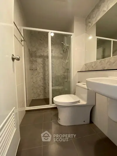 Modern bathroom with glass shower and sleek fixtures in contemporary apartment.