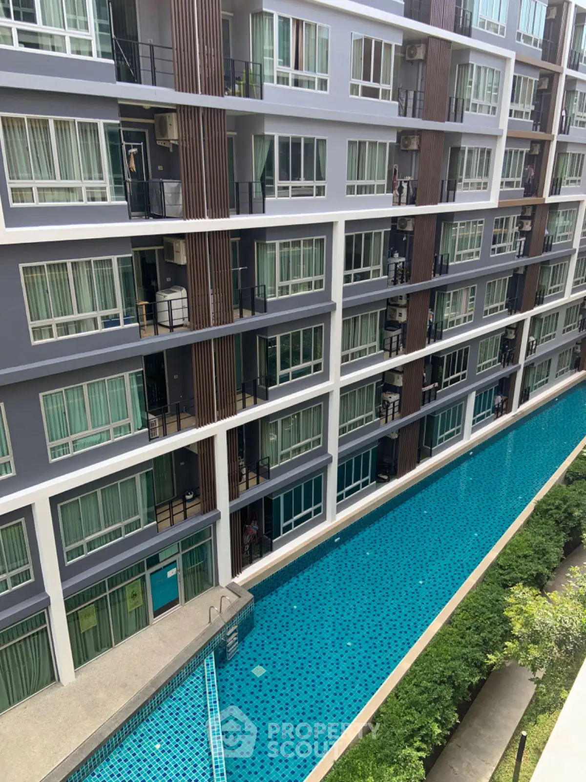 Modern apartment building with pool view and lush greenery, perfect for urban living.