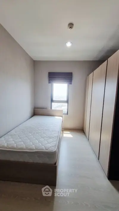 Cozy bedroom with single bed and large wardrobe, featuring natural light from window.