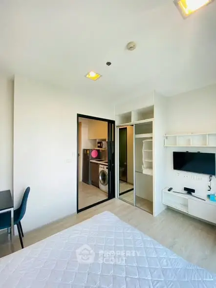 Modern bedroom with open view to kitchen, featuring built-in storage and sleek decor.
