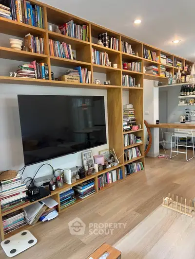 Spacious living room with built-in wooden shelves and large TV, perfect for modern family living.