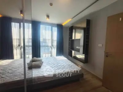 Modern bedroom with large windows and sleek design, featuring a wall-mounted TV and stylish decor.