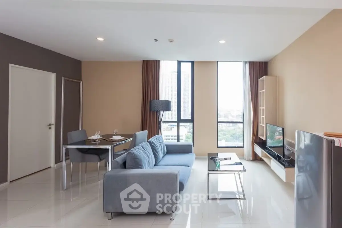 Modern living room with sleek furniture and large windows offering city views.