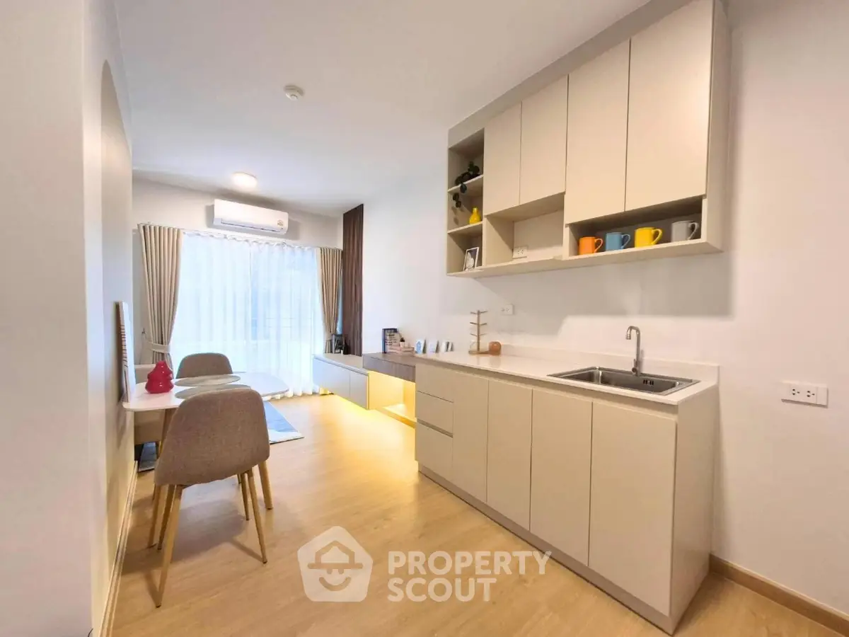 Modern kitchen with sleek cabinetry and dining area in bright apartment