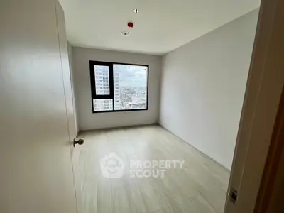 Spacious empty room with large window offering city view, perfect for customization.