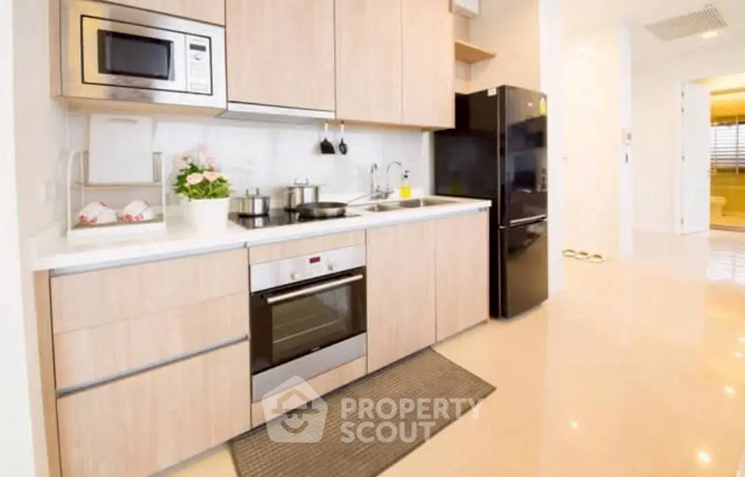 Modern kitchen with sleek appliances and wooden cabinetry, featuring an oven and microwave.