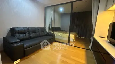 Modern living room with black leather sofa and glass partition to bedroom