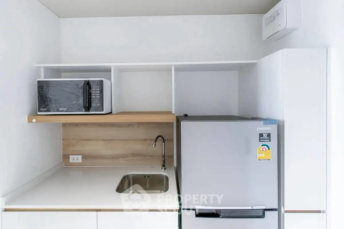 Modern compact kitchen with microwave and fridge in sleek white design