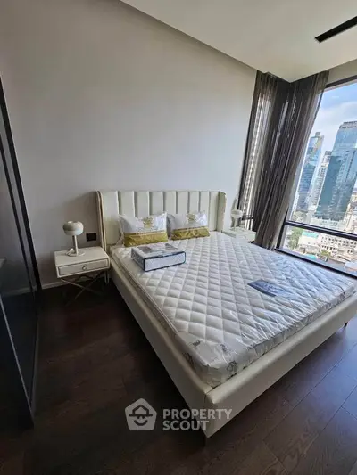 Luxurious bedroom with city view, elegant furnishings, and natural light.