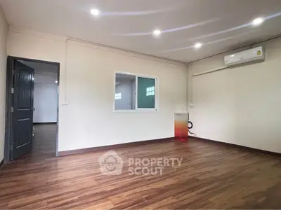 Spacious empty room with wooden flooring and air conditioning, perfect for customization.