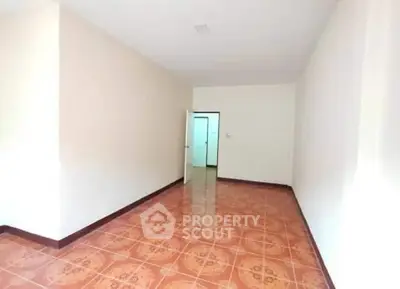 Spacious empty room with tiled flooring and open door, ideal for customization.