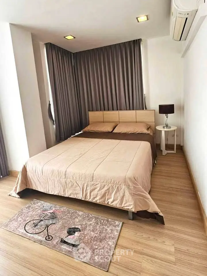 Cozy bedroom with wooden flooring, stylish curtains, and air conditioning, perfect for a comfortable living experience.