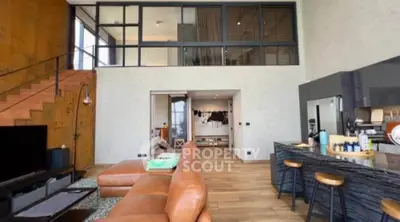 Spacious modern living room with leather sofa and open kitchen in stylish loft apartment.
