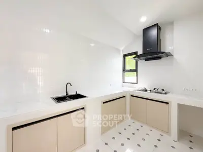 Modern kitchen with sleek design, featuring white cabinets, black sink, and gas stove for a stylish cooking space.