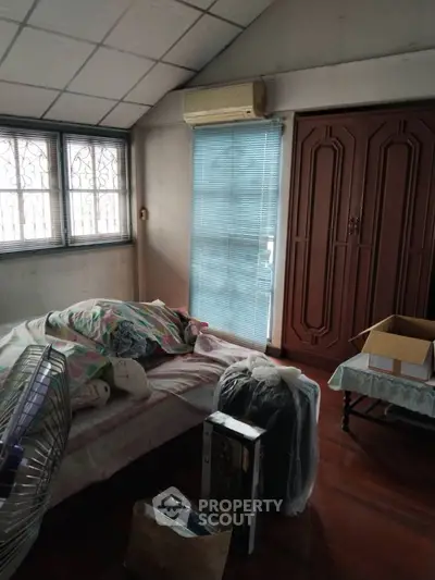 Cozy bedroom with natural light, air conditioning, and wooden wardrobe, ideal for comfortable living.