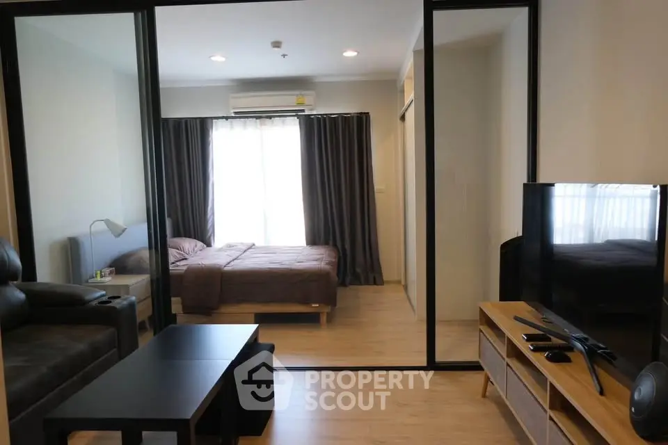 Modern living room with glass partition leading to cozy bedroom