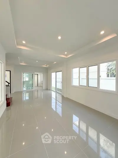 Spacious modern living room with large windows and glossy tiled floors, perfect for natural light and open living.
