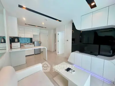 Modern open-layout living room with sleek white furniture and integrated kitchen appliances.