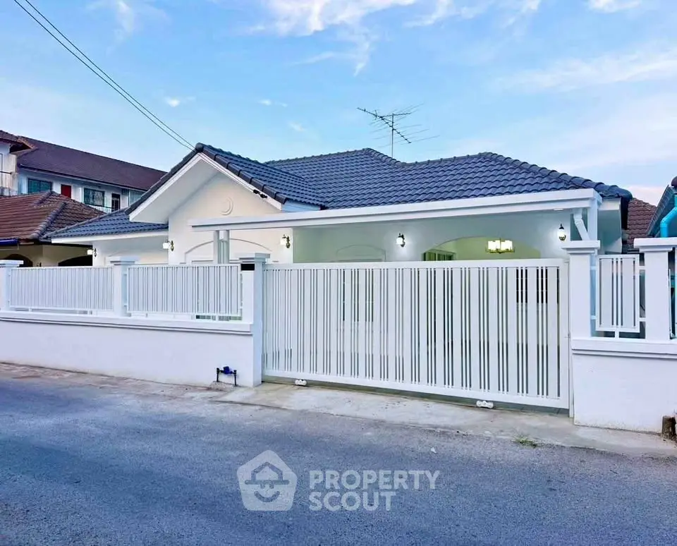 Charming single-story house with modern white fence and tiled roof in a serene neighborhood.