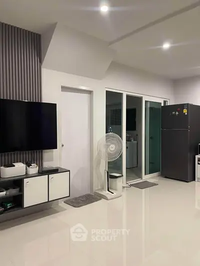 Modern living room with sleek design, featuring a wall-mounted TV and contemporary decor.