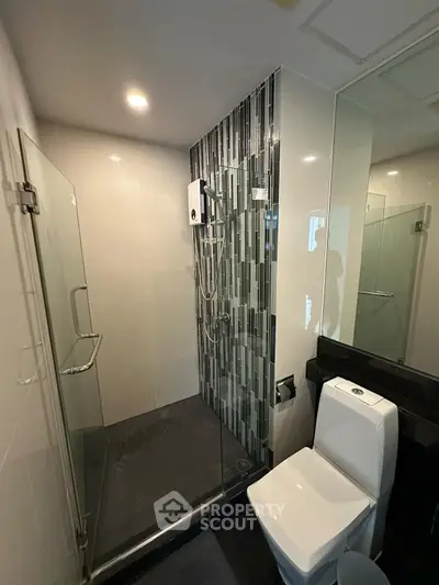 Modern bathroom with glass shower and sleek design in real estate property.