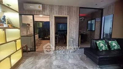 Modern living room with open kitchen and city view, featuring stylish decor and marble flooring.