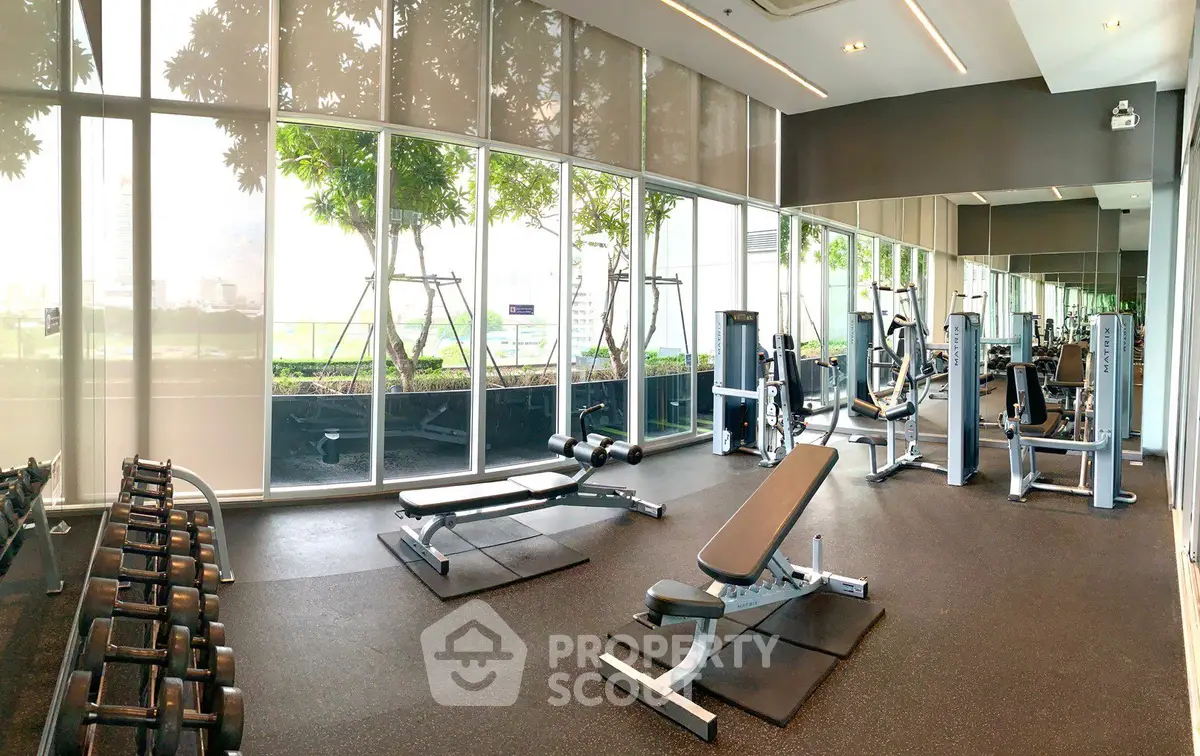 Spacious modern gym with state-of-the-art equipment and large windows offering a scenic view.