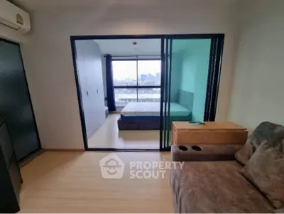 Modern studio apartment with sliding glass doors and city view.