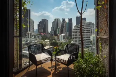 Stunning city view from a modern balcony with cozy seating, perfect for relaxation and urban living.