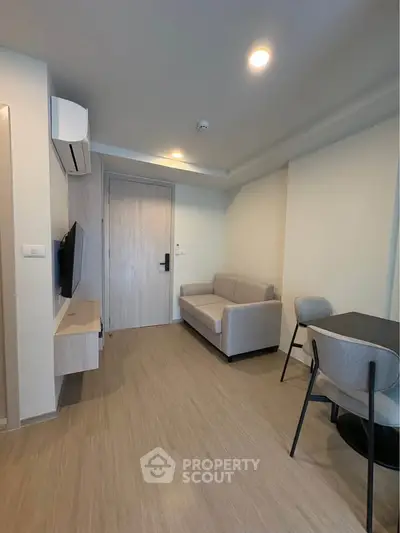 Modern living room with sleek furniture and wall-mounted TV in a cozy apartment.