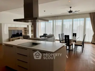 Spacious modern living room with open kitchen and large windows offering natural light.