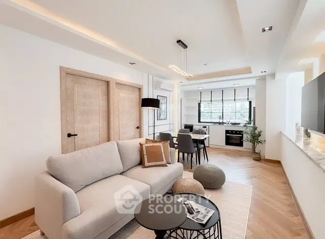 Modern living room with open kitchen, stylish decor, and natural light.
