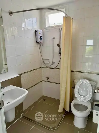 Compact bathroom with shower, sink, and toilet in modern apartment.