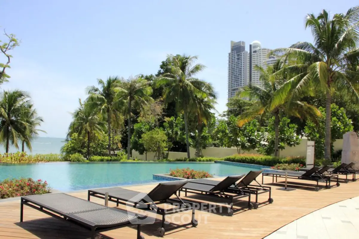 Luxurious poolside with palm trees and ocean view in a high-end residential complex.