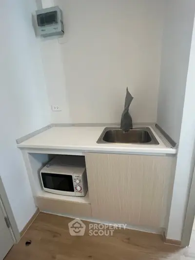 Compact kitchen corner with microwave and sink in modern apartment
