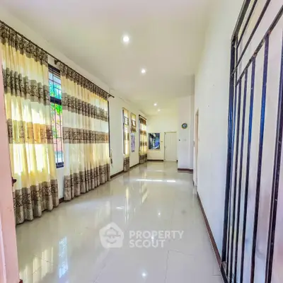 Spacious living room with large windows and elegant curtains, perfect for natural light and comfort.