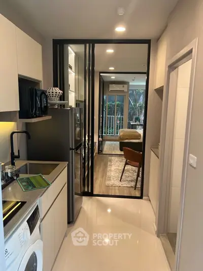 Modern apartment with sleek kitchen and cozy living area, featuring a washing machine and stylish decor.