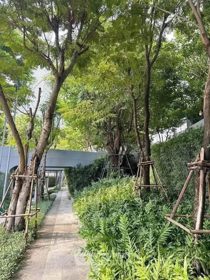 Lush garden pathway with mature trees and greenery in a serene residential complex.