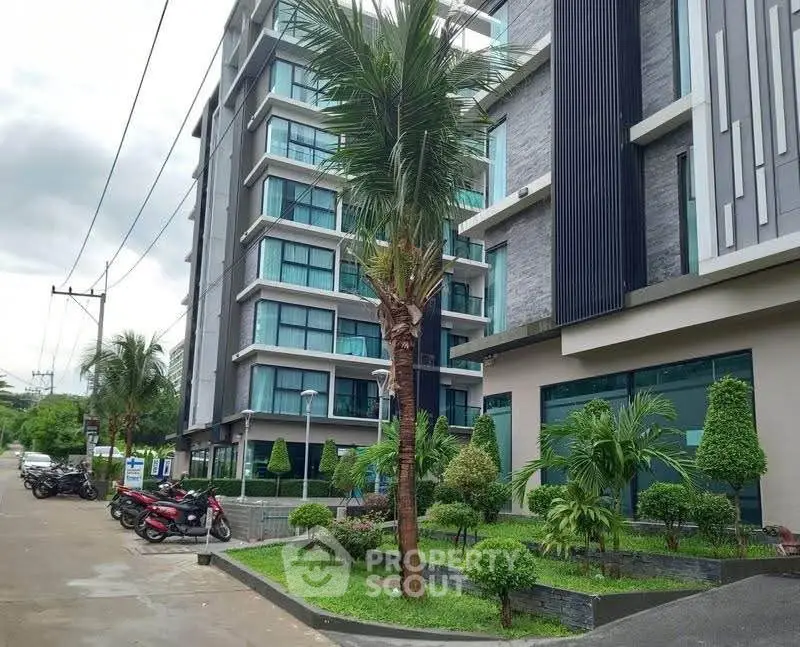 Modern apartment building with lush landscaping and palm trees, showcasing contemporary architecture.