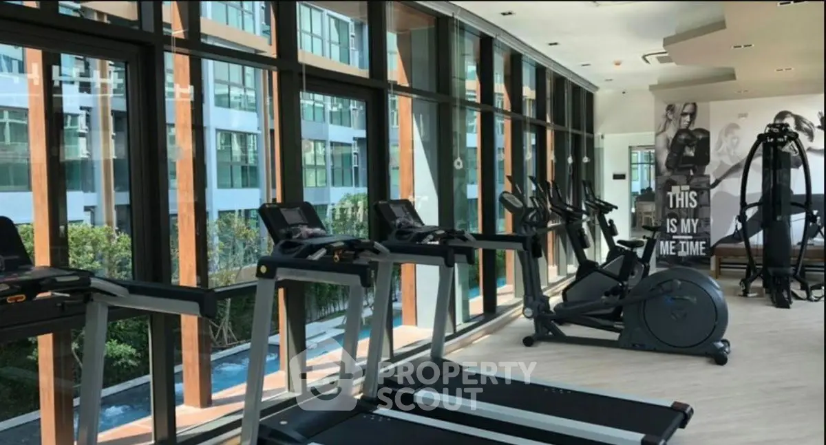 Modern gym with large windows and exercise equipment in luxury apartment building.