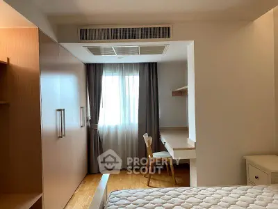 Cozy bedroom with natural light, wooden furniture, and a comfortable mattress, perfect for relaxation.