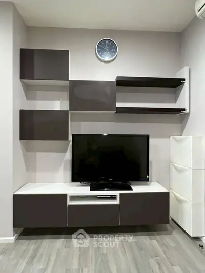 Modern living room with sleek TV unit and wall shelves, perfect for stylish urban living.