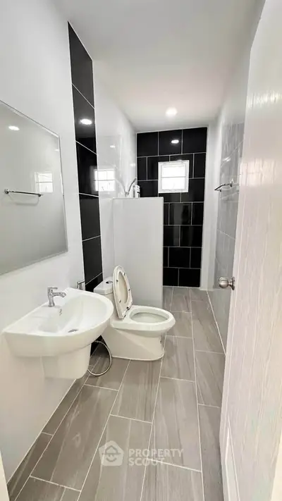 Modern bathroom with sleek black and white tiles, featuring a compact design and contemporary fixtures.