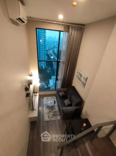 Modern loft-style living room with large window and city view.