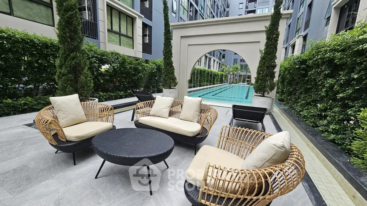 Luxurious poolside seating area with stylish wicker furniture in modern apartment complex.