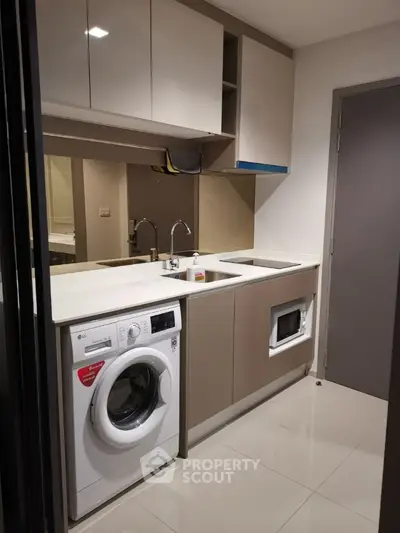 Compact modern kitchen with built-in appliances, sleek cabinetry, and neutral tones, perfect for urban living in a stylish apartment.