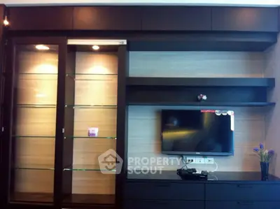 Modern living room with sleek TV unit and glass display shelves.