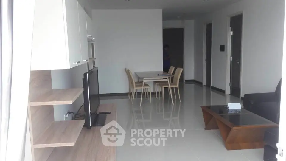Spacious modern living room with sleek furniture and dining area in open layout apartment.